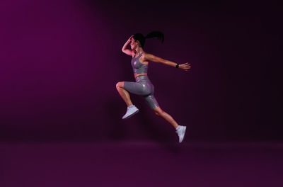 Side view of woman exercising against black background