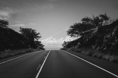 Empty road amidst trees against sky