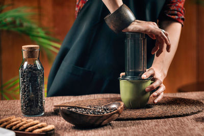 Midsection of woman making coffee in cafe