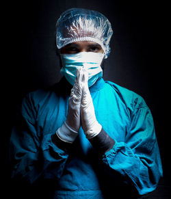 Portrait of young man wearing mask against black background