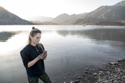 Woman putting mud on hands and face while enjoying outdoors in nature.