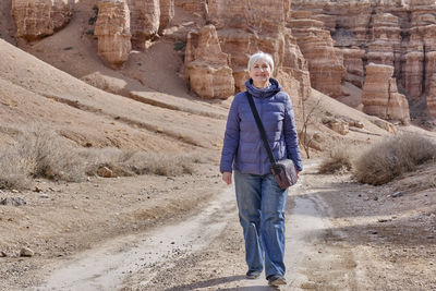 Senior woman walking along valley of castles gorge. charyn canyon national nature park in kazakhstan
