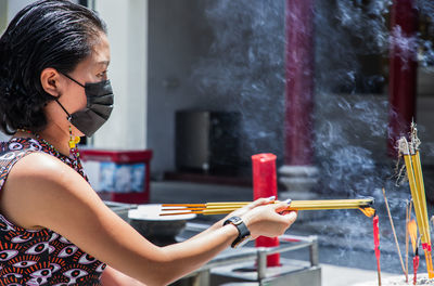 Side view of woman holding incense at temple