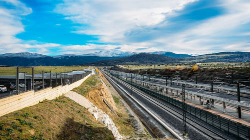 Railroad tracks by road against sky