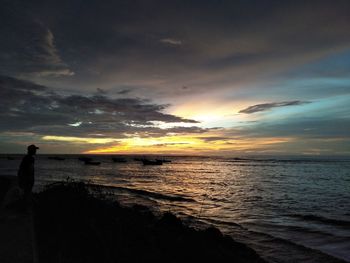 Silhouette man standing on beach against sky during sunset