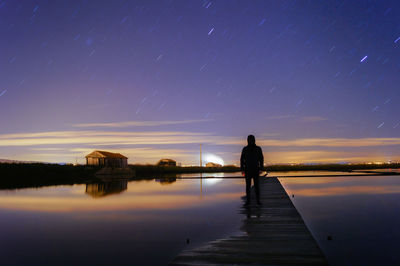 Man standing on jetty at night