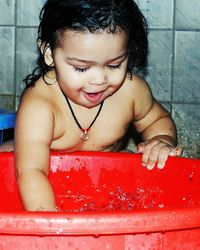 Close-up of cute shirtless boy playing with water in bucket