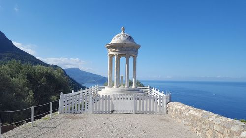 Built structure by sea against blue sky