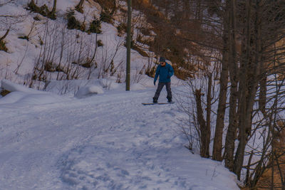 Full length of man snowboarding on snow covered land