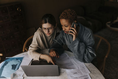 High angle view of non-binary couple doing finance on laptop at home