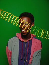 Portrait of young man standing against yellow background
