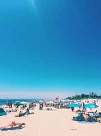 People on beach against clear blue sky