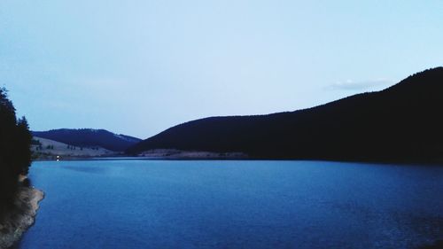 Scenic view of lake and mountains against clear blue sky