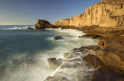 Scenic view of rocks on beach against sky