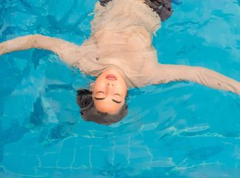 High angle view of woman floating on swimming pool