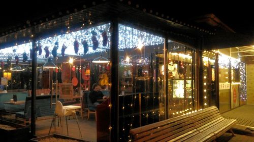 Illuminated restaurant seen through glass window at night