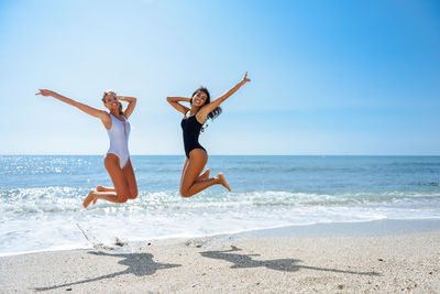 Cheerful friends enjoying at beach during sunny day