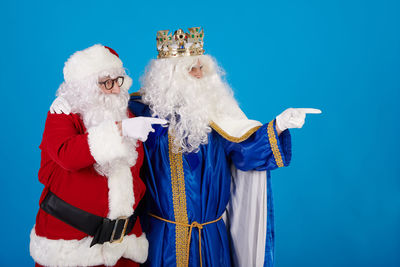 Portrait of woman wearing santa claus costume against blue background