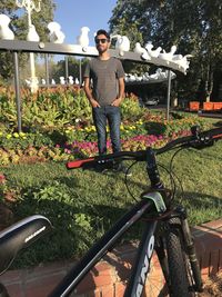 Man standing by bicycle against plants