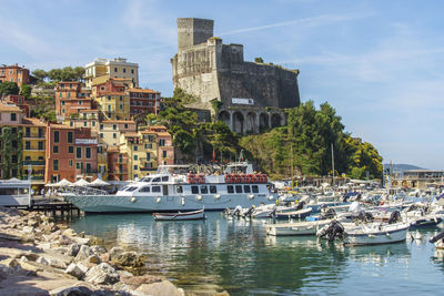 Sailboats moored in sea against buildings in city