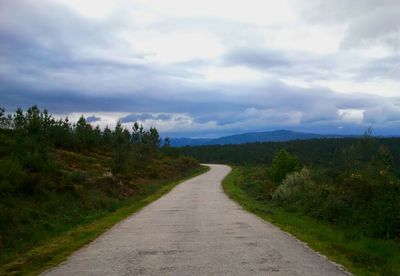 Empty country road against cloudy sky