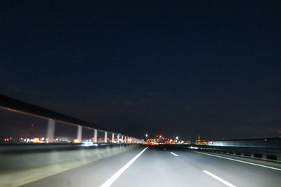 Illuminated light trails on road against sky at night