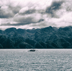 Scenic view of sea by mountains against sky