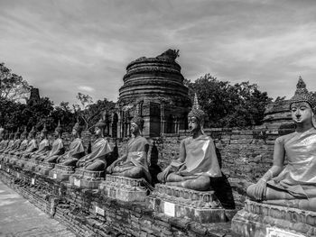 Statue by temple against sky