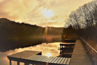 Pier over lake against sky during sunset