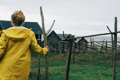 Rear view of woman standing on field against sky