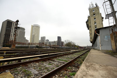 Railroad tracks amidst buildings in city against sky