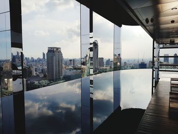 Digital composite image of swimming pool by buildings against sky