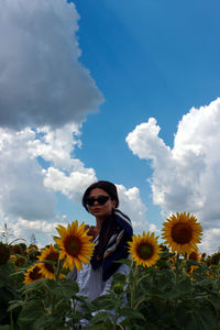 Low angle view of woman standing amidst sunflower field