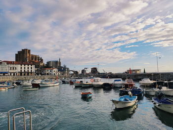 Sailboats moored in harbor against buildings in city