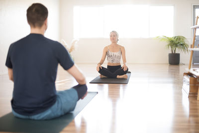 A girl and guy in a one on one yoga session.