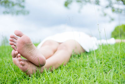 Low section of woman lying on grassy field