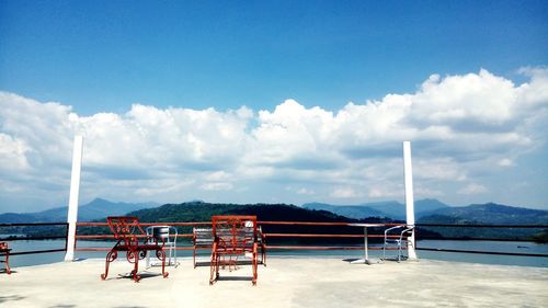 Deck chairs on beach against blue sky