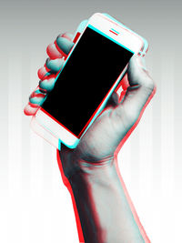 Close-up of hand holding smart phone against white background