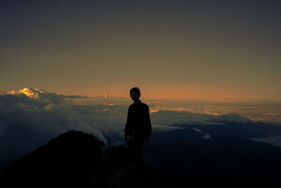 Man standing on mountain against sky during sunset