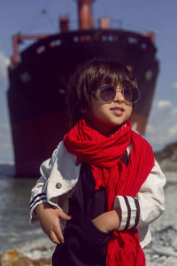 Fashionable boy child with long hair dance next to a large ship that ran aground 