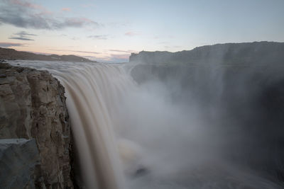 Scenic view of waterfall against sky during sunset