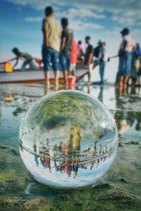 Reflection of people in water ball on glass