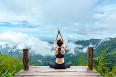 Full length of woman relaxing on mountain against sky