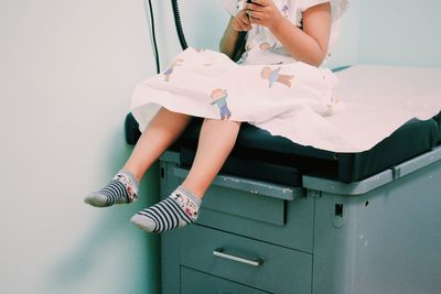 Low section of girl sitting on seat at hospital