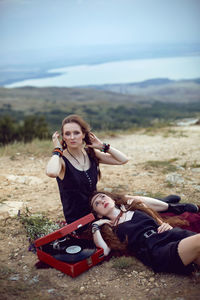 Two hippie woman are lying in a field on a mountain with an old gramophone on a vinyl record