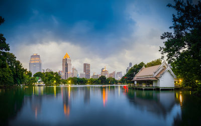 Reflection of buildings in lake against cloudy sky