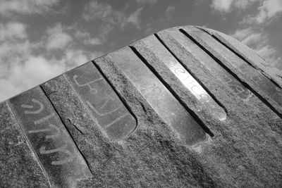 Low angle view of old bench on field against sky