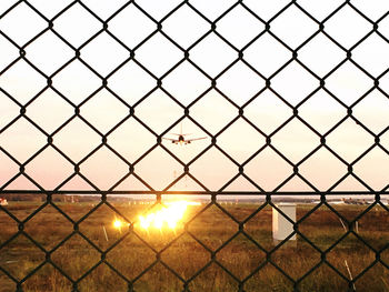 Close-up of chainlink fence against sky during sunset