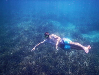 Shirtless man swimming in sea