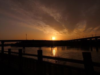 Silhouette bridge over river against sky during sunset